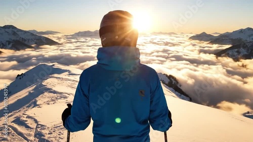 Skier on a snowy mountain summit watching the sunrise. Man looking over a sea of clouds in the alps. Winter adventure and exploration