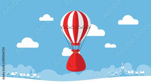 A red and white striped hot air balloon carries a large red sack over a snowy winter village landscape.