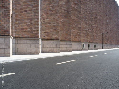 Fototapeta Naklejka Na Ścianę i Meble -  Brick building, paved road, small vents and street lamp