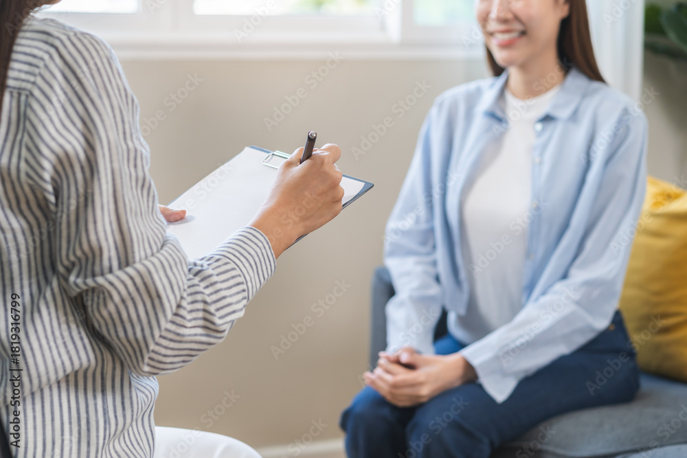 Fototapeta premium Psychology concept, depression. Happy smile asian young woman patient mental therapy explain symptom with psychologist while doctor taking notes at clinic. Psychology with sick mental health person.