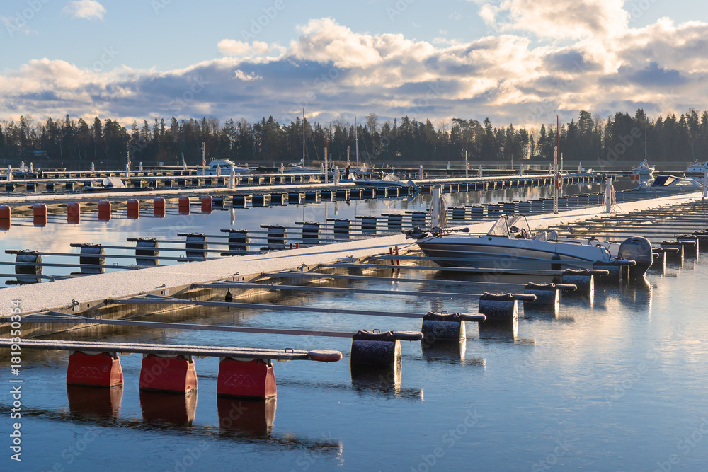 Obraz premium Sea marina at winter, abandoned boat, empty harbor , winter season in Finland, winterizing, winter season in Northern country, cold conditions