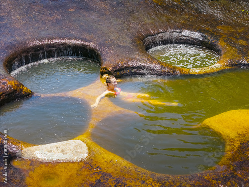 Aerial view of a woman bathing in the crystalline waters of the natural pools amidst the rugged, sun-drenched rock formations, Guadalupe, Santander, Colombia.