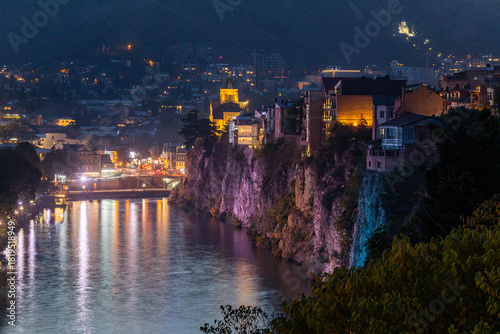 A view of Tbilisi at night: the high bank of the Mtkvari (Kura) River, the Metekhi Church, traditional Georgian houses, and beautiful lighting.