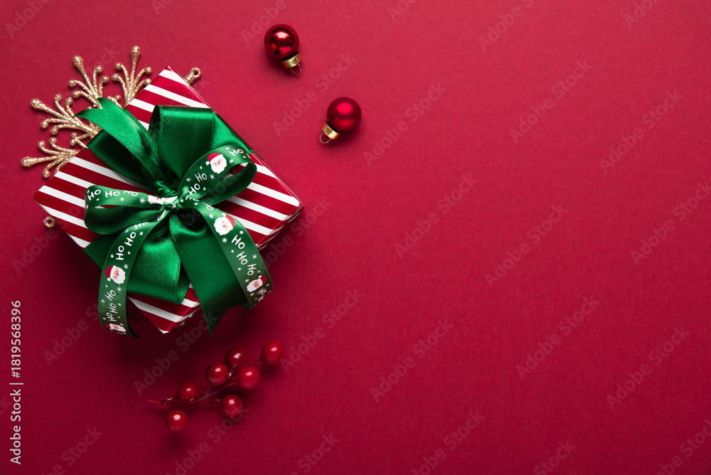 Obraz premium Merry Christmas and Happy Holidays greeting card, frame, banner. New Year. Red Christmas ornaments and gift box, present on red background top view. Xmas holiday festive theme. Christmas decoration