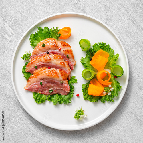 Delicious roasted duck breast fillet with golden crispy skin, with pepper and rosemary, top view on ceramic white plate, rustic concrete rustic background
