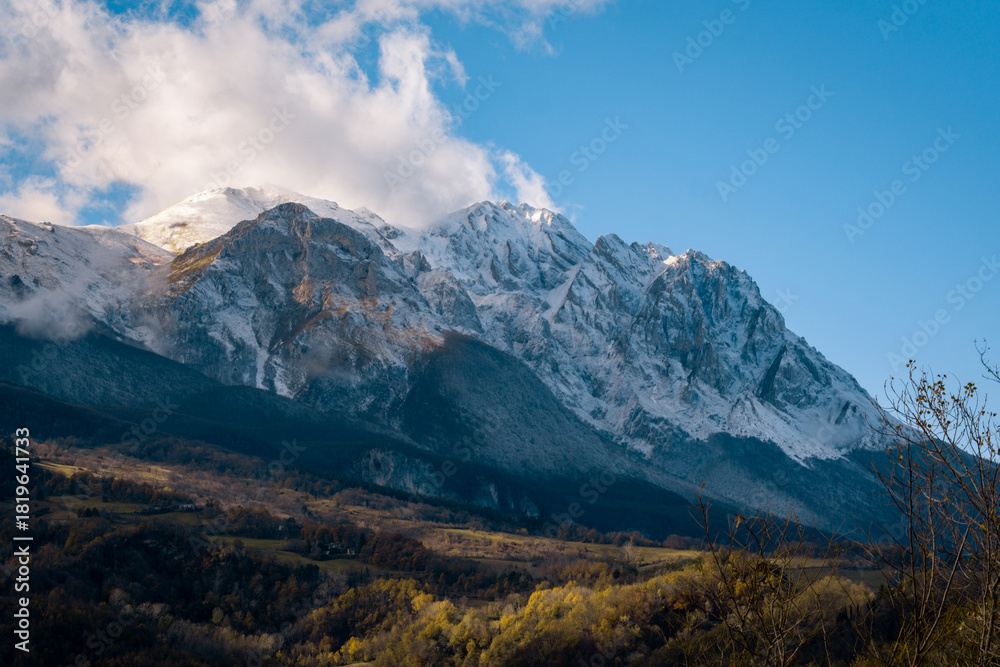 Obraz premium Snow-capped Gran Sasso d'Italia mountains glowing under sunlight with autumn colored valley below