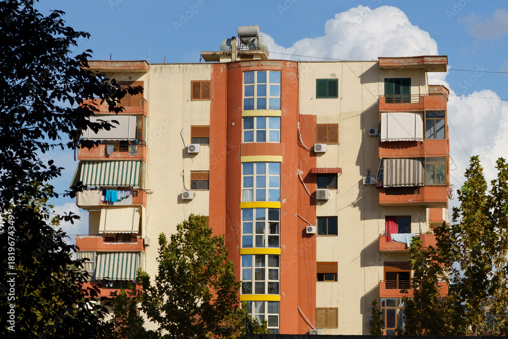 Fototapeta premium A renovated stucco home with older air conditioners stands on a lively city street. Perfect for rental listings, real estate agencies, foreign buyers, and modernizing urban neighborhoods.