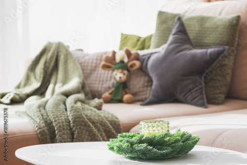 Cozy Living Room with Crocheted Reindeer Toy on Sofa and Christmas Holiday Candle Decor on Table
