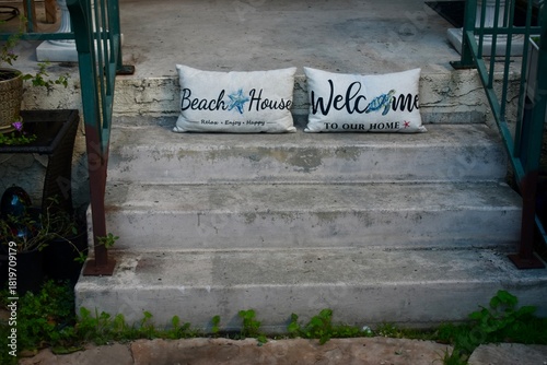 Pair Beach House and Welcome Pillows on cement staircase 