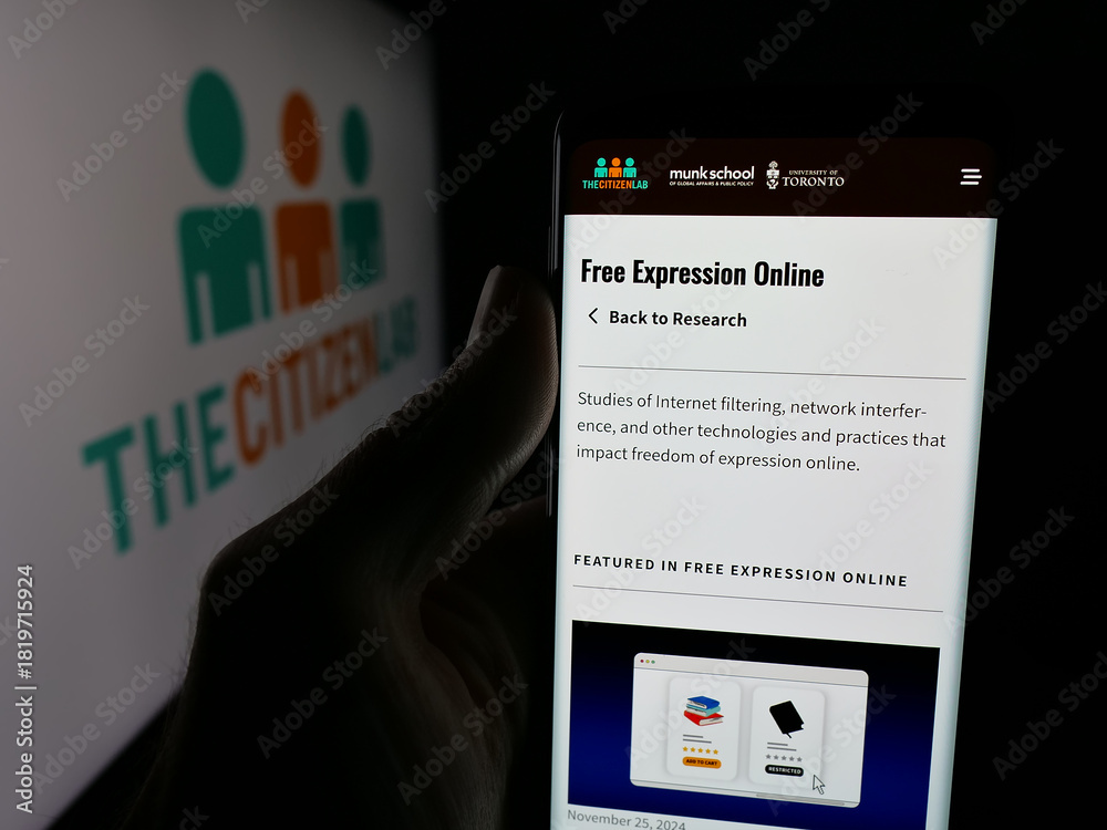 Fototapeta premium Stuttgart, Germany - 11-19-2025: Person holding cellphone with webpage of Canadian research laboratory Citizen Lab on screen in front of logo. Focus on center of phone display.