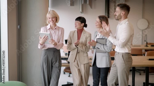 Colleagues gather in a bright office, sharing smiles and congratulations on achieving a big goal together.