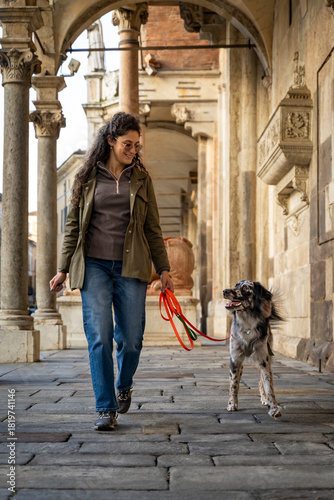 Woman and dog enjoying a walk together along an old city portico