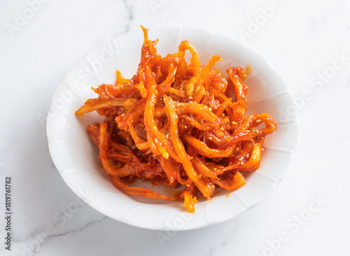 Spicy squid salad with sesame seeds served in a white bowl. Perfect for food bloggers looking for Asian meal ingredients.