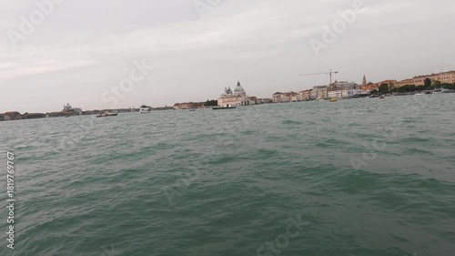 Wide view of the Venetian lagoon with historic architecture on the horizon and gentle waves under an overcast sky