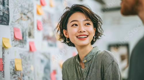 Asian female HR specialist reviewing a resume clipped to a board, candidate (Caucasian) explaining details, open-space office