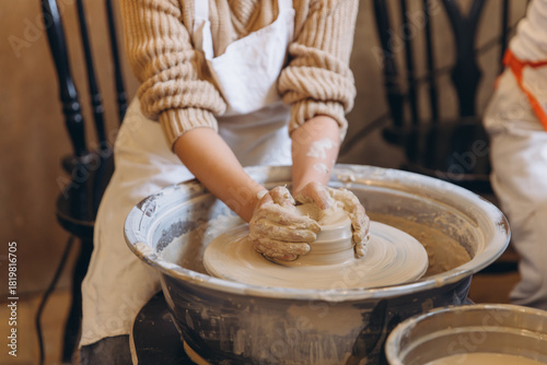 Child hands creating pottery on spinning wheel