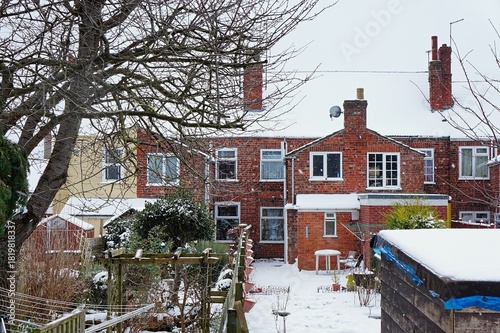 Row of terraced houses & back gardens with falling snow during winter