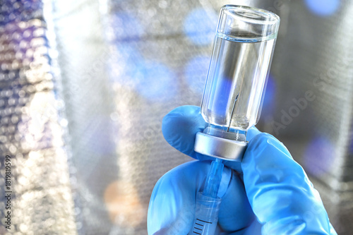 Medical personnel filling a syringe needle with generic vaccine booster from vial