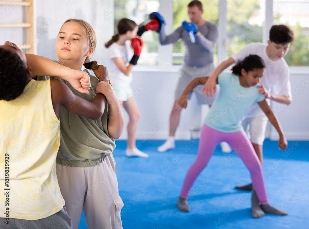 Fototapeta premium Girls and boys learns to do power grip with trainer during a self-defense lesson in the gym