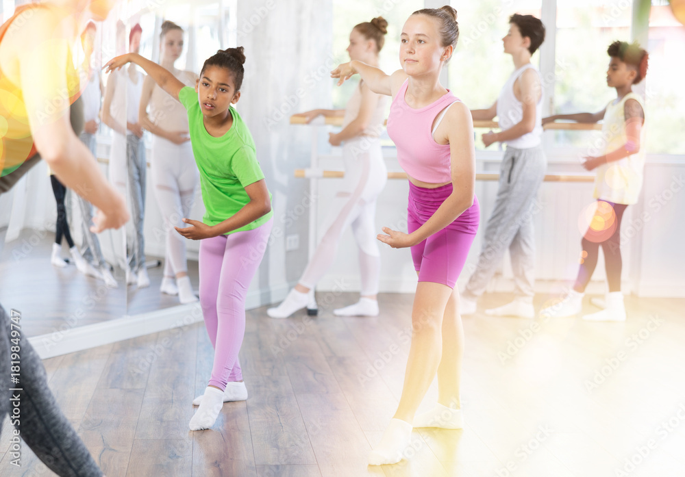 Fototapeta premium Group of boys and girls teenage dancers rehearsing ballet moves in dance studio