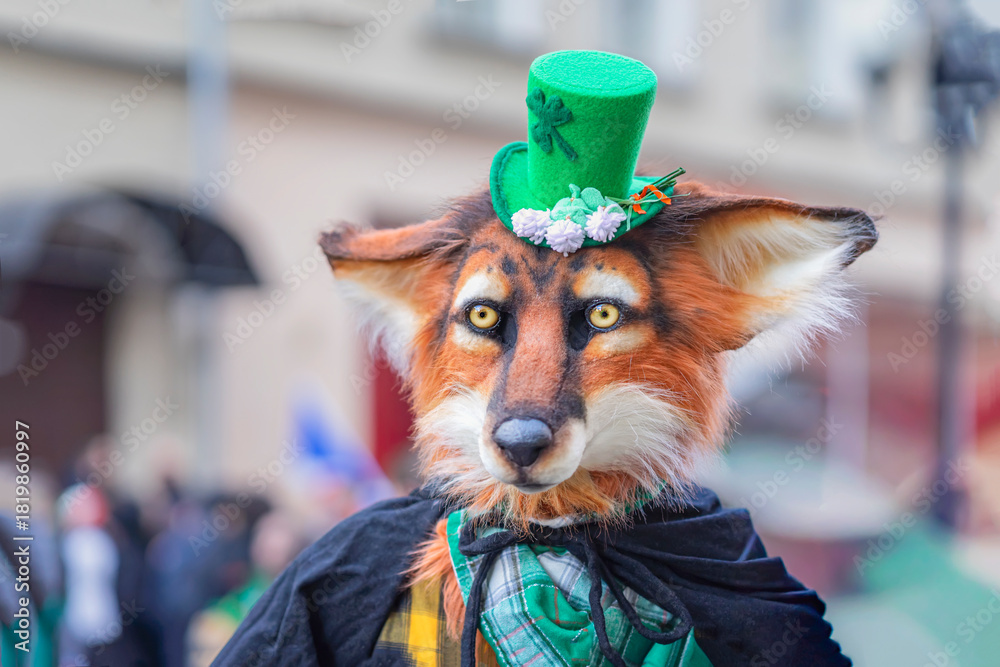 Naklejka premium Participant in the St. Patrick's Day Parade. Person in fox mask costume and green top hat standing among people crowd outdoors. Creative masquerade, quirky holiday costume