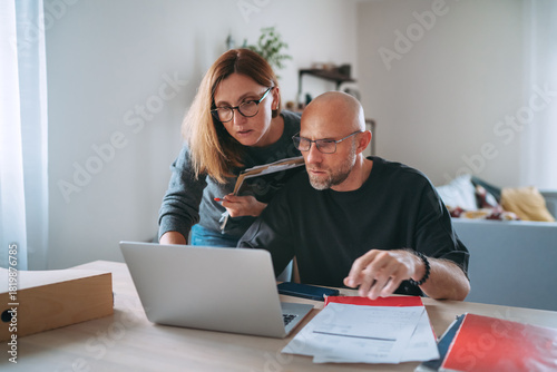 Canvas Print Small business owners focused on financial planning at home office, reviewing paperwork and managing online tasks on laptop, showing teamwork, responsibility and modern entrepreneurial workflow