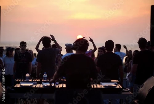Experience the energy of a vibrant beach party with a DJ spinning tunes as the sun sets, creating unforgettable summer memories for a lively crowd