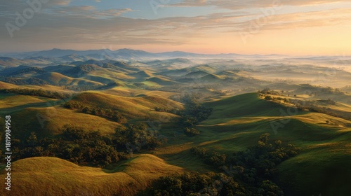 Aerial View of Undulating Golden Hills at Sunrise, Misty Valleys and Vibrant Sky.