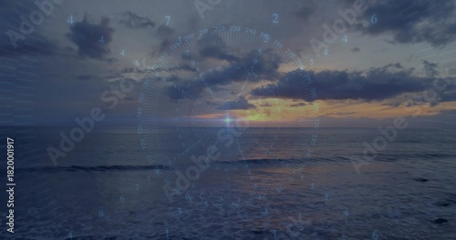 Glowing sun with centered HUD overlay reflecting on ocean at sunset, showing right coastline © vectorfusionart