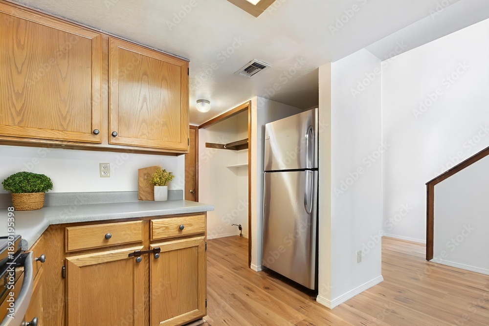 Fototapeta premium A kitchen with wood cabinets and a stainless steel fridge