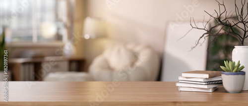 Fototapeta Naklejka Na Ścianę i Meble -  Book and succulent pot and vase on wooden counter table across sofa and frame in blurred living room