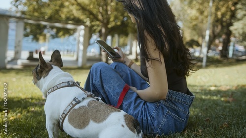 Woman Using Smartphone While Sitting with Dog Outdoors