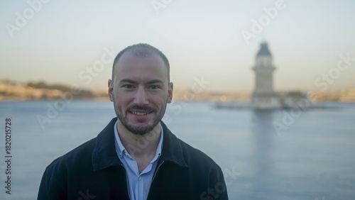 Man Smiling by the Water with Historical Landmark
