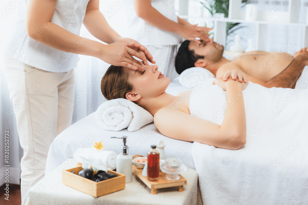 Fototapeta premium Caucasian couple enjoying relaxing anti-stress head massage and pampering facial beauty skin recreation leisure in dayspa modern light ambient at luxury resort or hotel spa salon. Quiescent