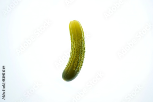 A single dill pickle, slightly curved, stands vertically against a bright white background.