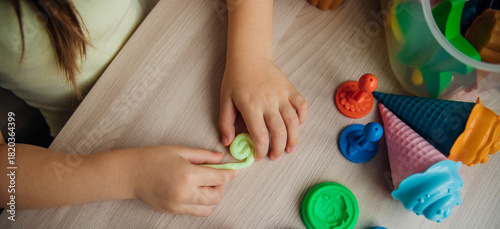 A little girl makes figurines out of colored airy plasticine, modeling dough. Hobbies for children's creativity, educational activities, development of fine motor skills of hands.