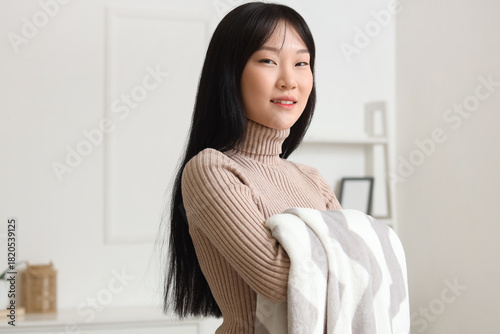 Young Asian woman with soft plaid smiling at home