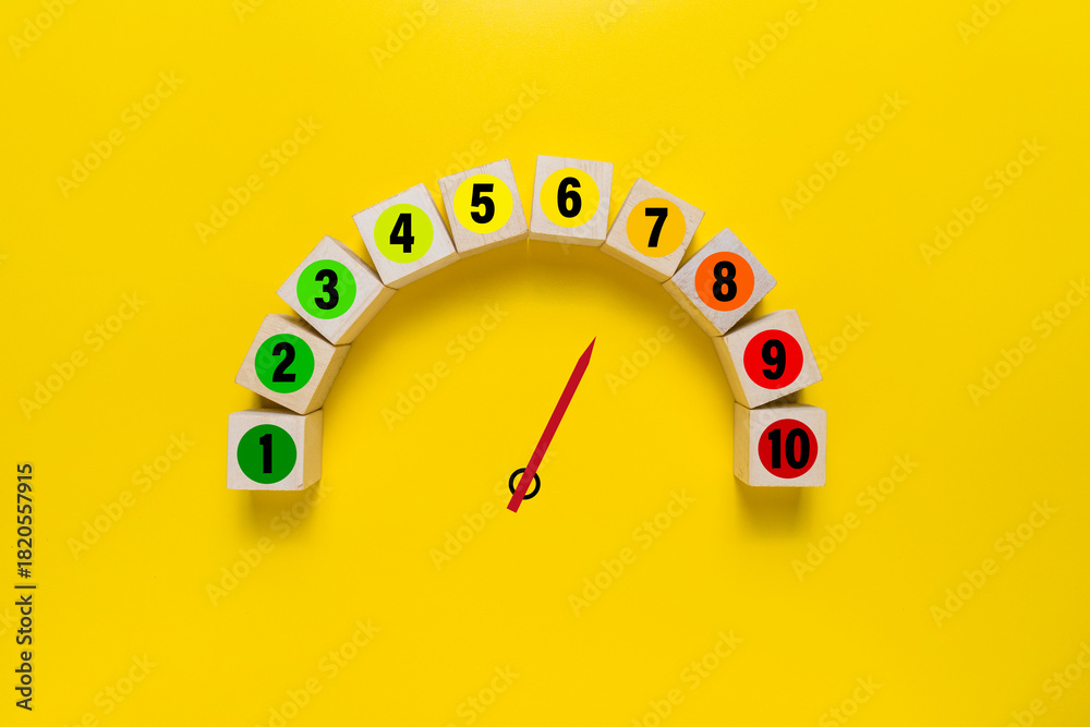 Fototapeta premium risk level meter indicator from low to high with 1 to 10 scale numbers on wooden blocks isolated on yellow background. concept of risk management