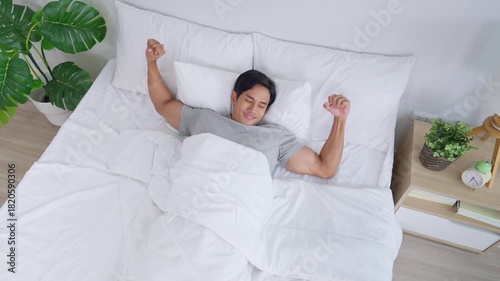 Asian handsome young man getting up from sleep on bed in the morning.