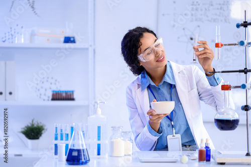 Pretty young African-American female chemist with mortar and test tube workin...