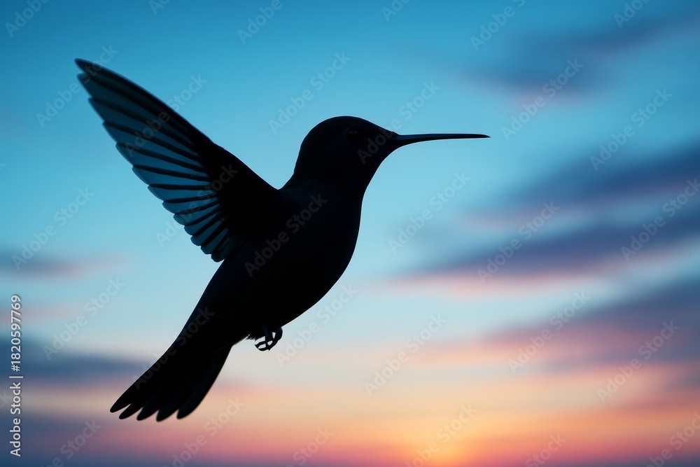 Fototapeta premium Silhouette of hummingbird in flight with wings spread wide against a vibrant sunset sky and soft clouds in colorful twilight light background. Ai generative