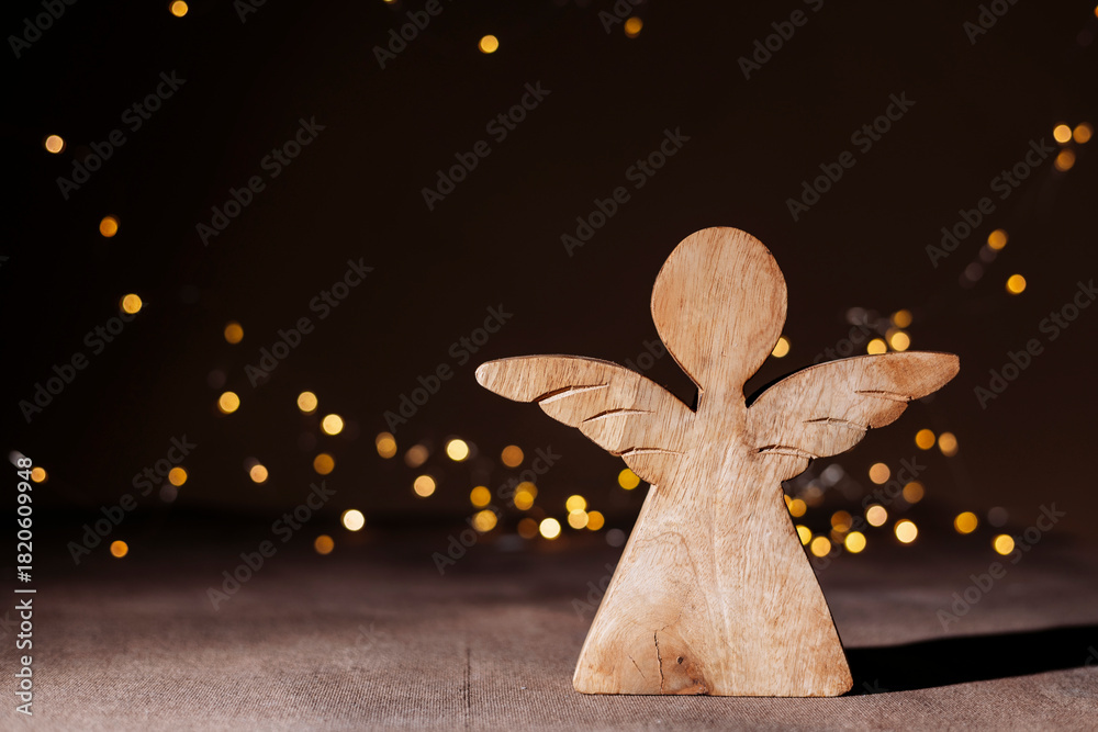 Naklejka premium Rustic wooden angel figurine on holiday lights