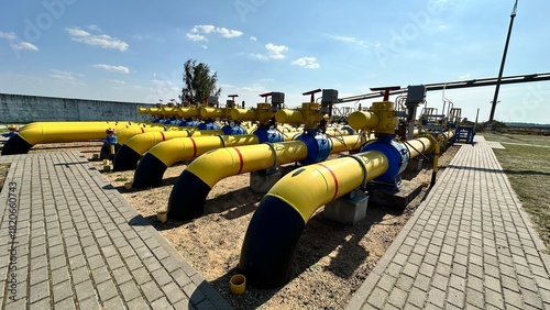 The photo shows yellow and blue gas pipes with black stripes that enter the ground from above. Gas is supplied through the pipes under high pressure.