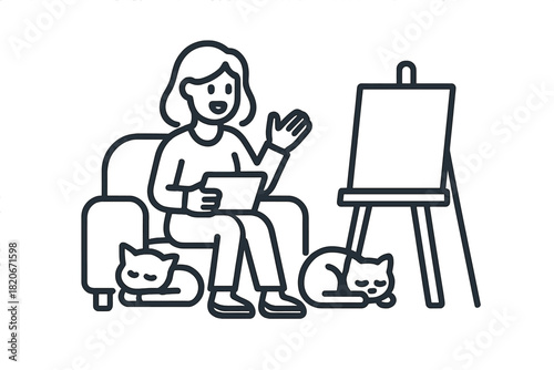 Female artist working on a digital tablet at home surrounded by her sleeping cats and an easel
