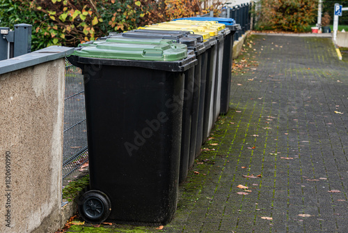 Colorful recycling bins aligned along a street in autumn