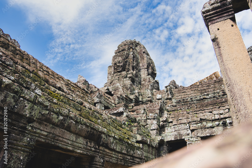 Fototapeta premium Ancient stone tower depicting a smiling face of lokeshvara at the bayon temple, part of the angkor thom complex in siem reap, cambodia, showcasing impressive khmer architecture
