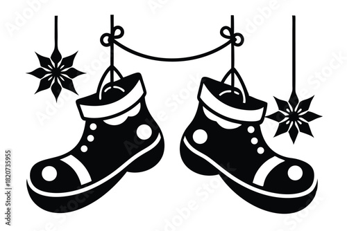 Two black silhouette boots hanging from a rope with two snowflake ornaments