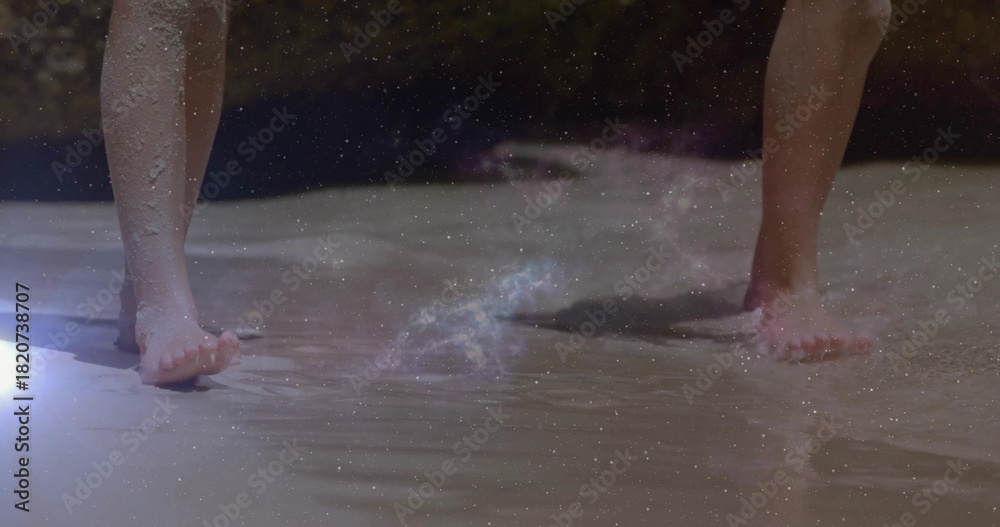Naklejka premium Wading two kids' bare feet in shallow shoreline water at beach, showing footprints and lens flare