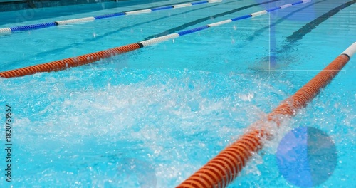 Splashing middle lane creating frothy bubbles at lap pool, with orange and blue white lane dividers