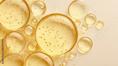 Close-up of transparent yellow oil droplets on a light background. The droplets vary in size and contain small bubbles, creating a textured appearance.